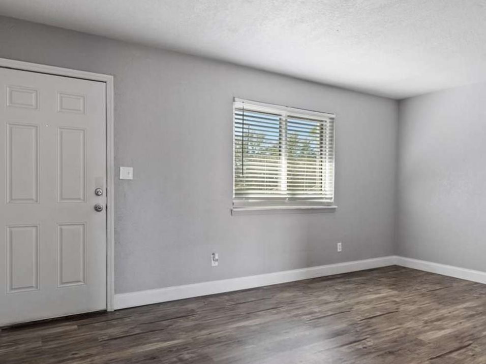 A room with a white door and a window with blinds.